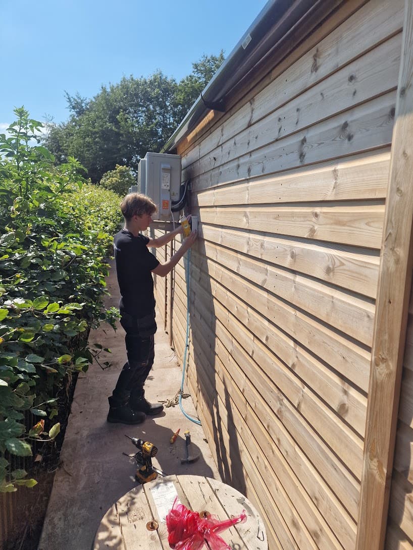 Electrician installing an external rotary isolator for an air-conditioning unit