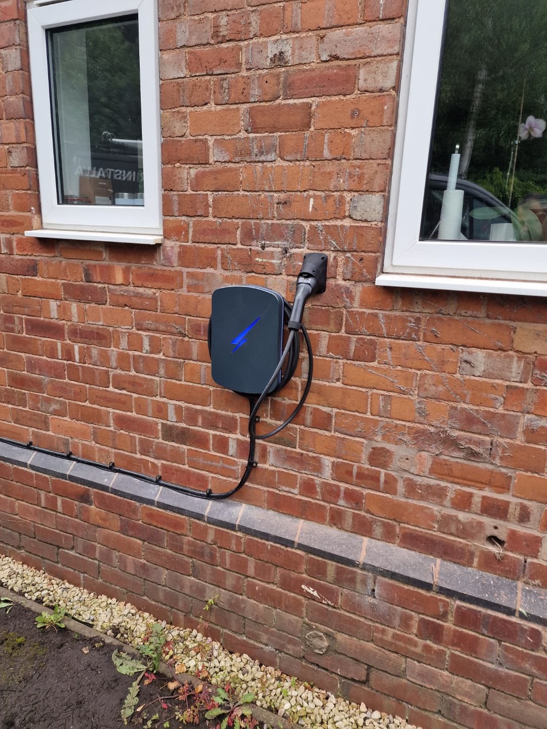 Hypervolt Home 3 Pro installed on brick wall with tethered lead and holster