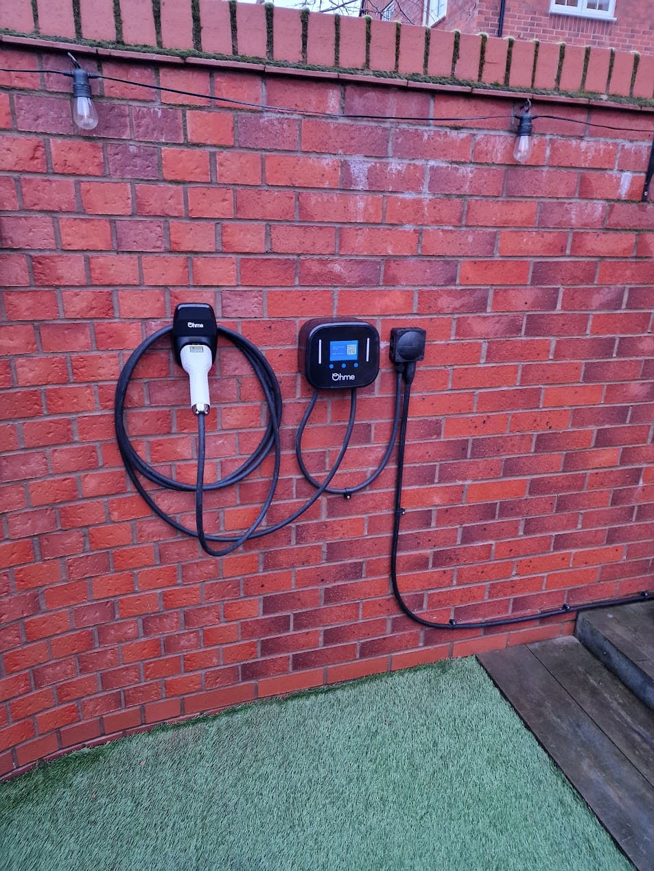 Ohme Home Pro installed on brick wall with tethered lead and holster